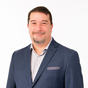 a man wearing a suit and tie smiling at the camera